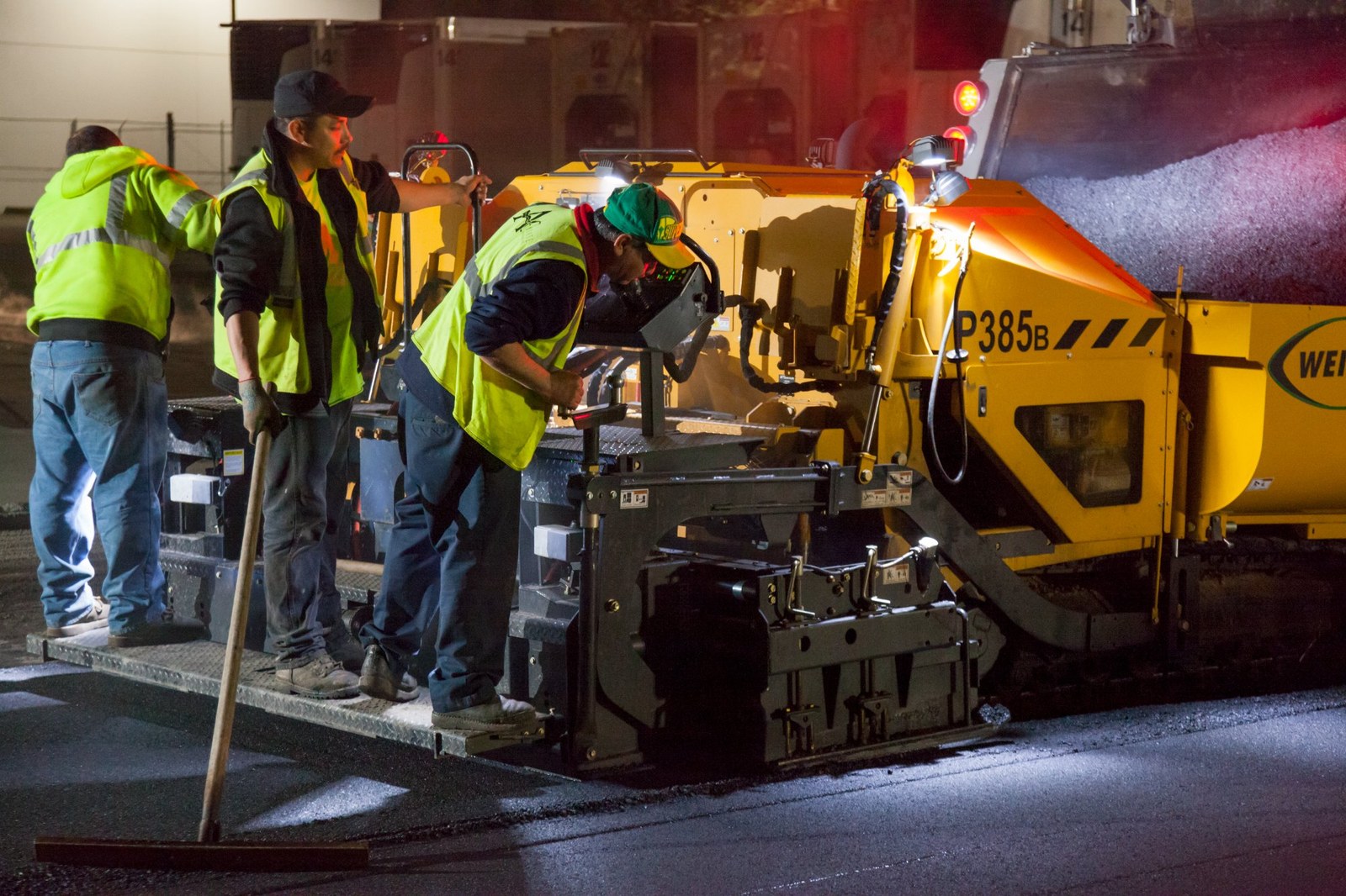 Paving crew operating heavy machinery on commercial lot